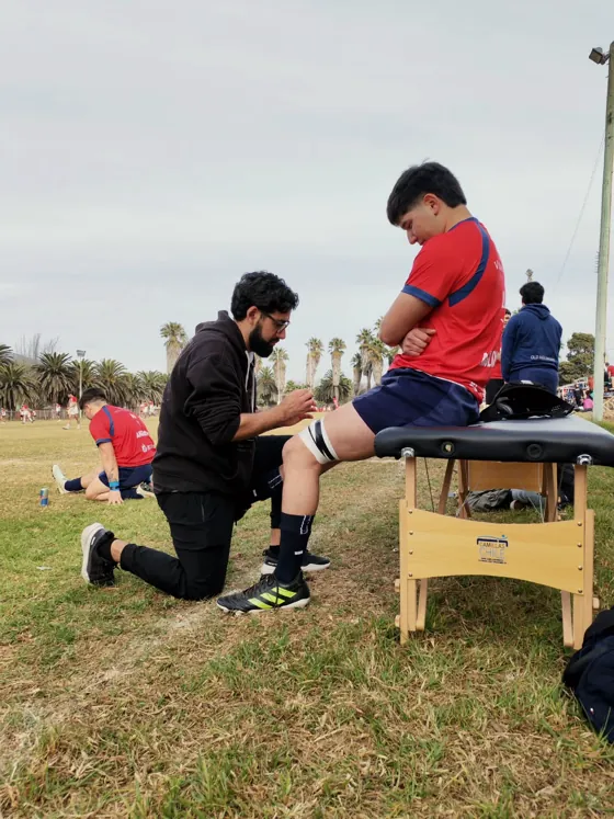 Kinesióloga de Kinesis atendiendo a un jugador de rugby en la cancha